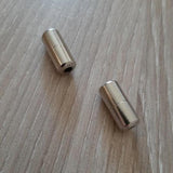 Gros plan sur deux embouts métalliques pour lacets élastiques, permettant un laçage sans nœud