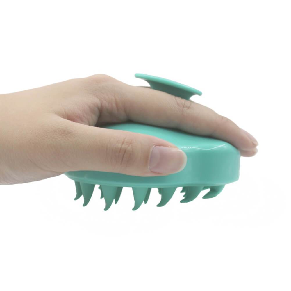 Brosse à shampoing à picots en silicone tenue en main par sa poignée ergonomique