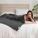 Couverture lestée 4 kg gris foncé utilisée sur un lit pour favoriser la relaxation et le calme.