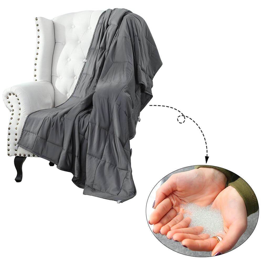 Couverture lestée gris foncé sur un fauteuil, avec détail des microbilles de verre du garnissage