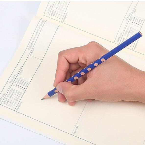 Crayon ergonomique triangulaire avec repères de préhension, tenu correctement pendant l'écriture