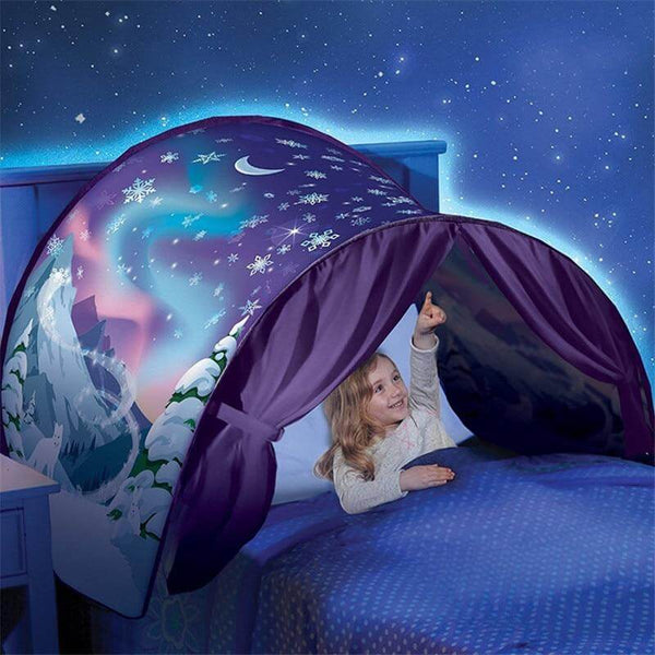 Une fillette assise sur son lit, pointant le décor polaire et les flocons de neige du paravent de lit
